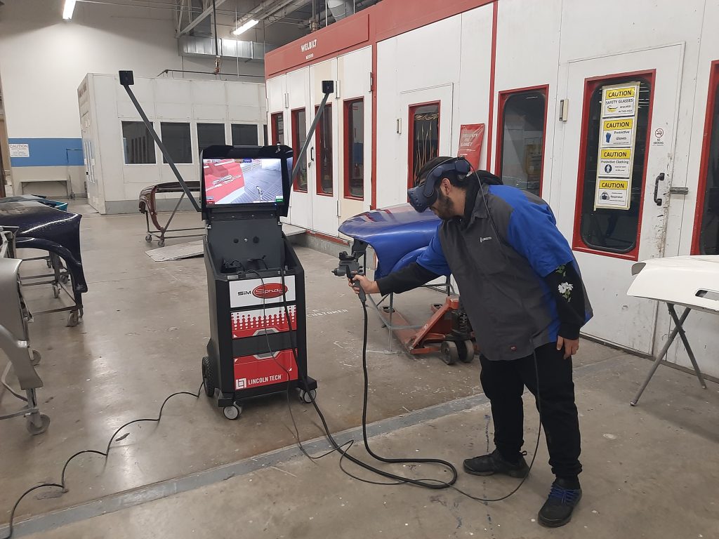 Lincoln Tech student practices painting a car door using SimSpray at the East Windsor, CT campus.